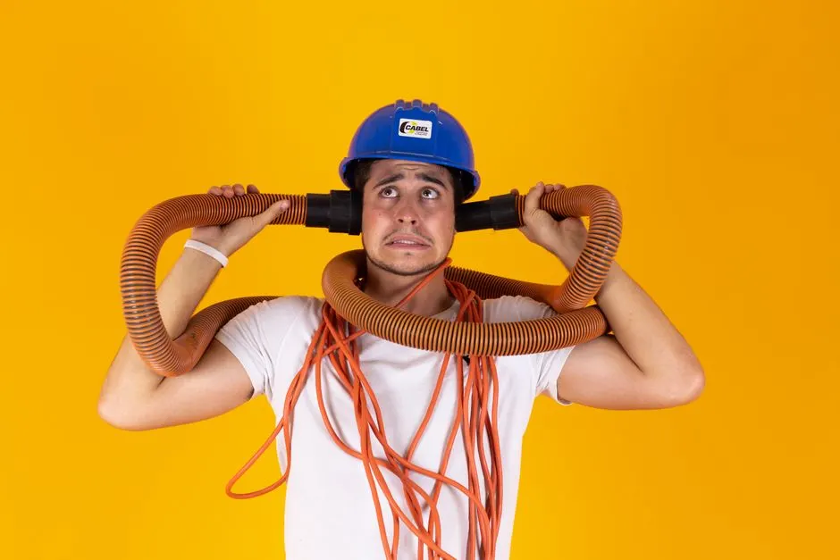 Man with blue helmet and orange hoses looks confused against a bright yellow background.